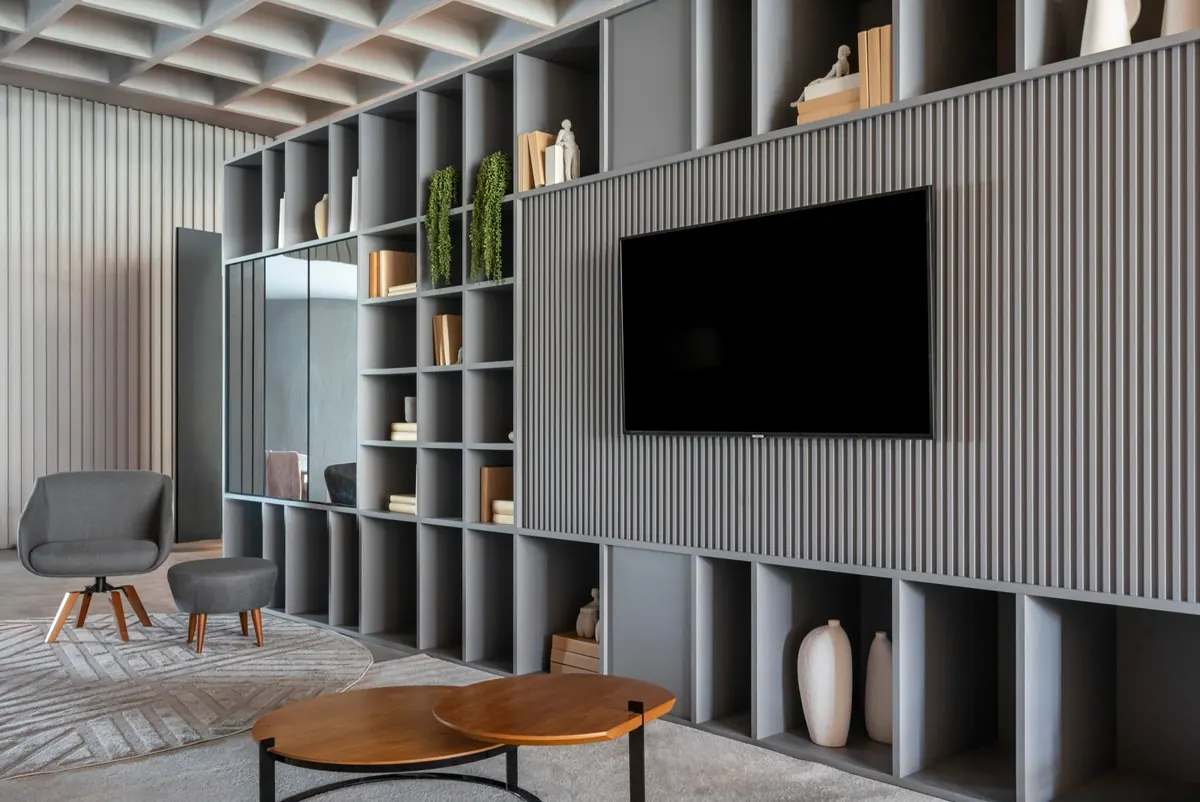Sala com estante vazada cinza e painel de TV